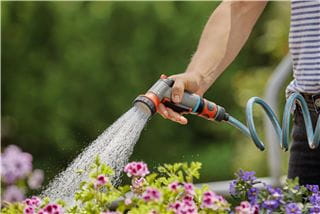 A person watering their plants with a GARDENA water hose