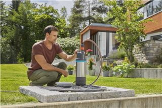A man in the garden using a GARDENA submersible pressure pump