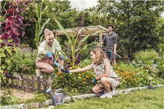 A young couple working together in the garden with their daughter
