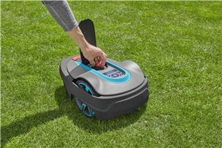 A person presses a button on their robotic lawnmower
