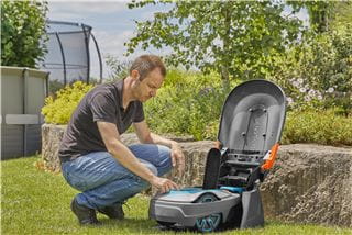 A man operating a robotic lawnmower garage in its garage