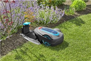 A GARDENA robotic lawnmower at its docking station in the garden