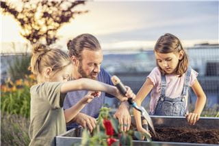 A father and his two young daughters gardening together