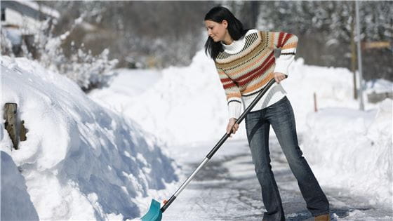 A woman shoveling snow with a Gardena combisystem snowshovel