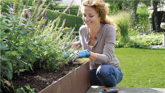 A woman working in a flowerbed with Gardena combisystem products