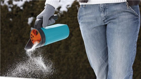 A person using a Gardena Small Caster to spread salt and grit