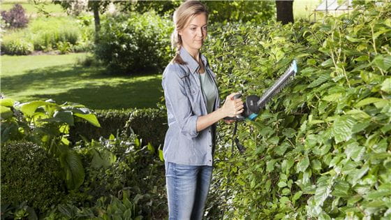 A woman trimming her hedge with a Gardena Hedge Trimmer