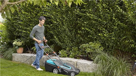 Young man mowing his lawn with a Gardena Electric Lawnmower