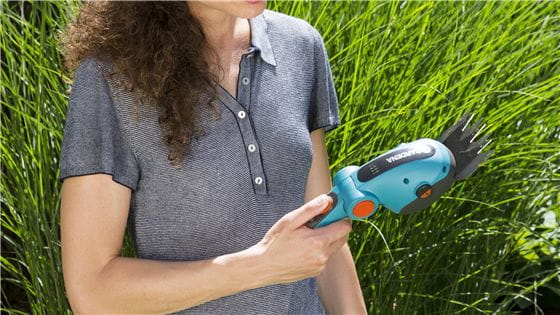 Woman holding a battery grass shear in her hand
