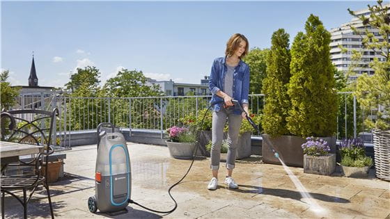 A woman using the Gardena Pressure Washer to clean the tiles on her balcony