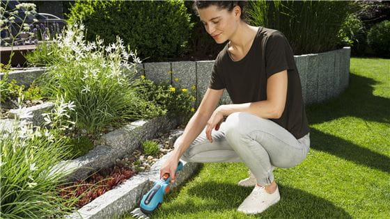 Woman cutting the edge of her lawn with a GARDENA Battery Grass Shear