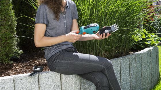 Woman converting battery grass shears into battery shrub shears