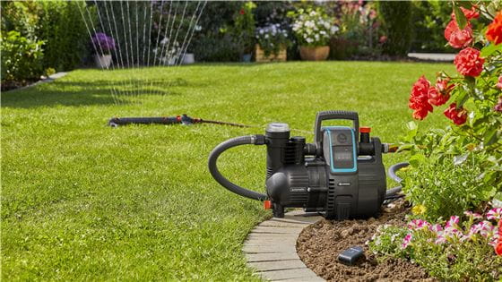 Automatic Home and Garden Pump in a garden with a sprinkler watering the lawn in the background