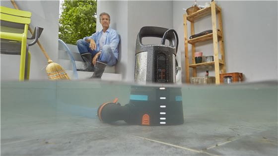 A man watching a drainage pump cleaning a flooded cellar 