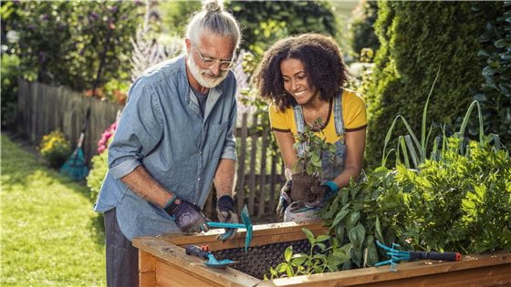 An older man and a young woman working on a raised bed with Gardena Combisystem Products 
