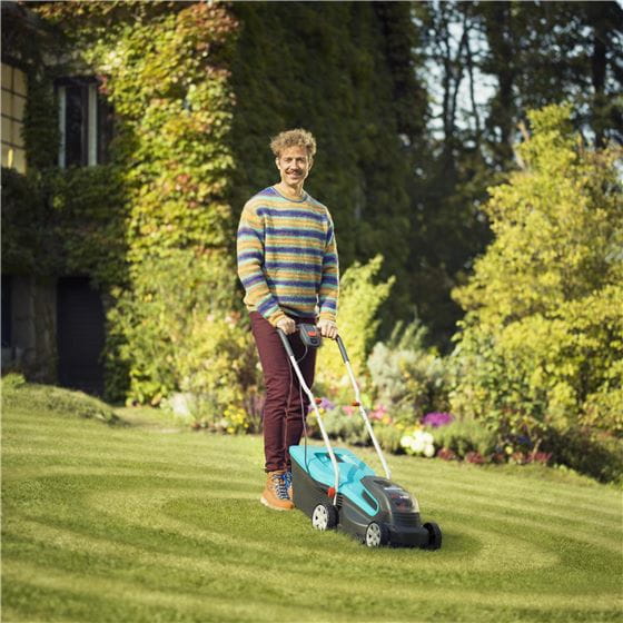 A man in the garden with a battery lawnmower